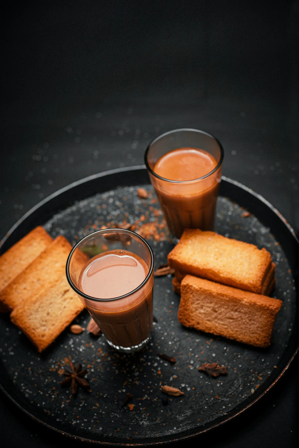 A warmly lit Indian meal set with tea and bread on a dark tabletop
