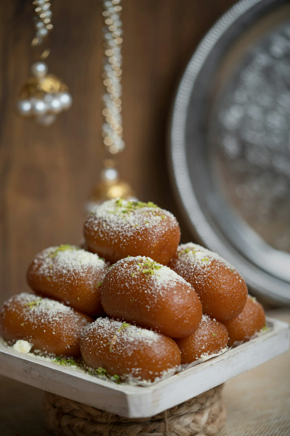 A bowl of warm syrup-soaked Indian sweets under amber restaurant light