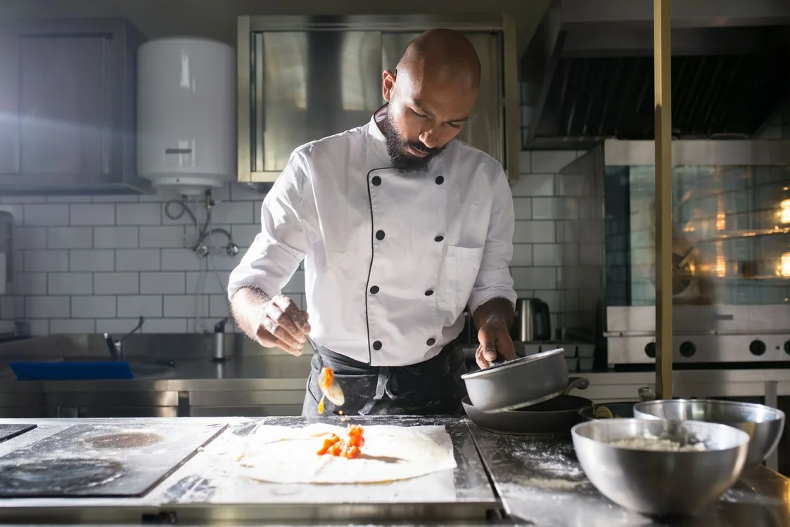 Chef concentrating on a dish in a professional kitchen; illustrative portrait for this fictional restaurant demo